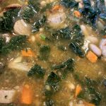 Beans, greens and sausage soup in a bowl.