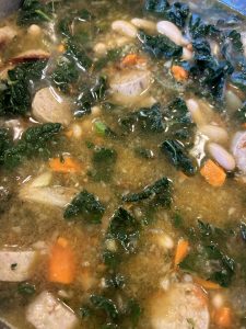 Beans, greens and sausage soup in a bowl.